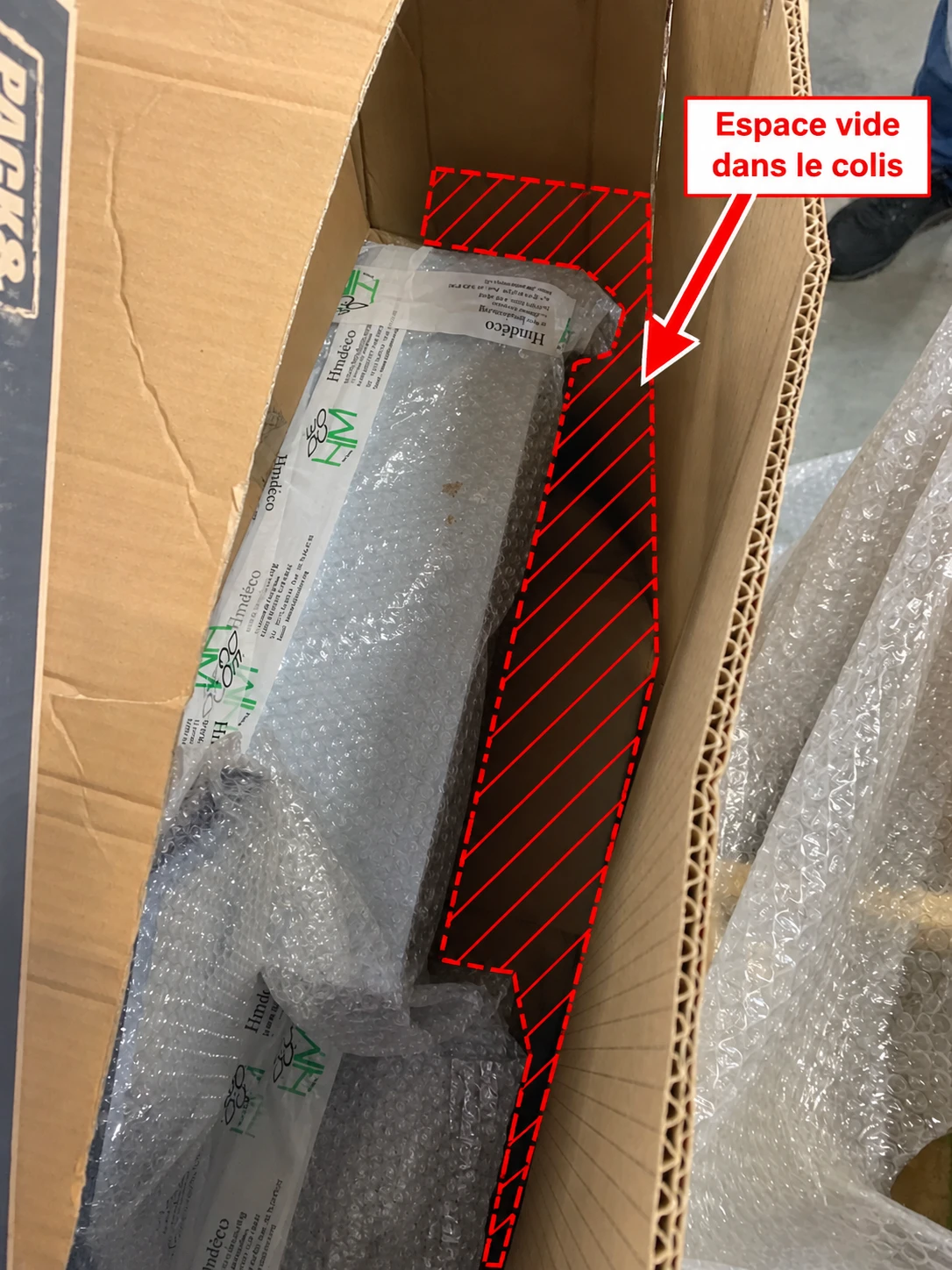 Carton allongé contenant un produit emballé dans du papier bulle, avec une zone vide annotée « Espace vide dans le colis » sur toute la longueur restante du carton.